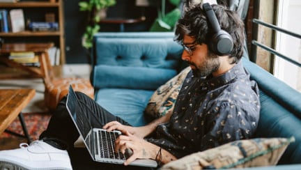 Individual sitting on sofa with headset infront of his laptop
